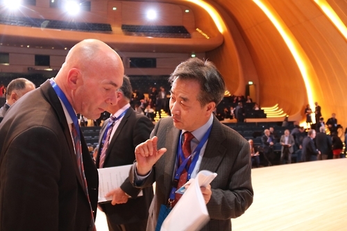 韩联社社长朴鲁晃（右）在会议休息时间与英国国家通讯社总编彼得·克利夫顿交谈。（韩联社） 