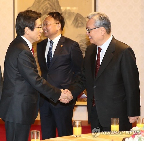 3月3日上午，在首尔，代行总统职权的韩国总理黄教安（左一）在高层党政会上与执政的自由韩国党领导人握手。（韩联社）