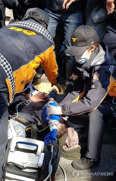 3月10日，在韩国宪院门外，消防员们正对集会受伤人员采取急救措施。（韩联社）