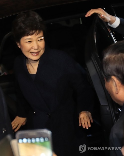 朴槿惠乘车抵达私邸后下车，面带微笑。（韩联社）