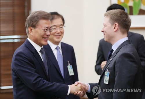 韩国总统文在寅（左一）与到访的美国白宫亚洲事务资深主管马修·波廷杰亲切握手。（韩联社/青瓦台提供）