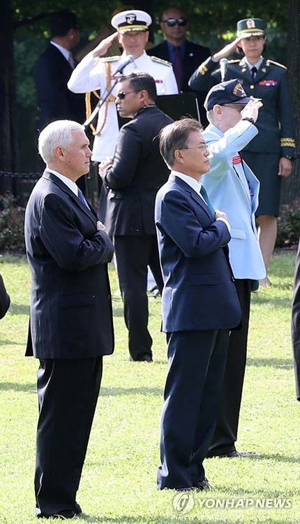 当地时间6月30日上午，在华盛顿国家广场，文在寅和彭斯在向韩战纪念碑献花后对韩美国旗敬礼。（韩联社）