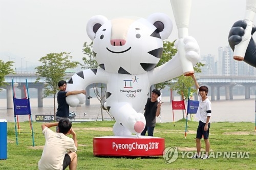 资料图片：市民与平昌冬奥会的吉祥物Soohorang雕像合影留念。（韩联社）