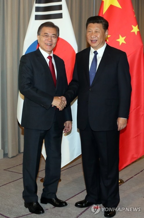 当地时间7月6日上午，在德国柏林，韩国总统文在寅（左）和中国国家主席习近平会晤，双方亲切握手。（韩联社)