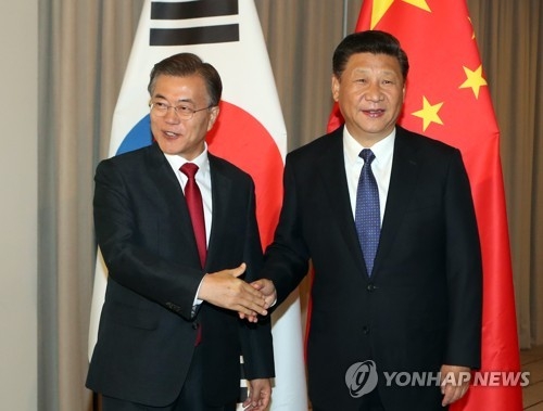 资料图片：当地时间7月6日，在德国柏林，韩国总统文在寅（左）与中国国家主席习近平握手合影。（韩联社）