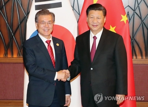 资料图片：当地时间11月11日，在越南岘港，韩国总统文在寅（左）与中国国家主席习近平在会谈前握手合影。（韩联社)