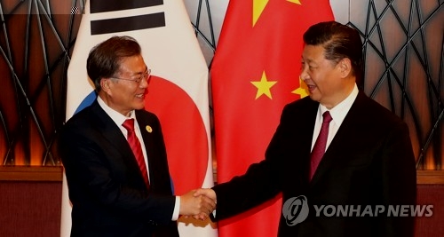 资料图片：11月11日下午，在越南岘港，文在寅（左）和习近平在APEC峰会期间举行的首脑会谈上亲切握手。（韩联社）