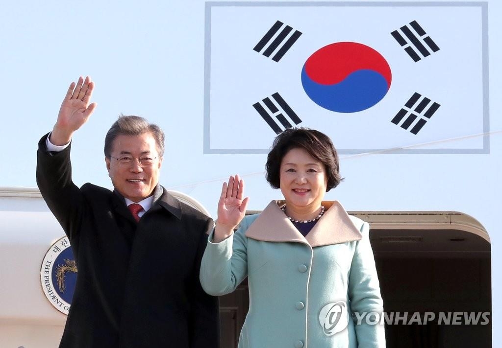 12月13日上午，在中国北京首都机场，韩国总统文在寅夫妇抵达后向众人挥手致意。（韩联社）