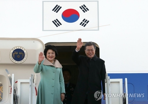 12月13日上午，在首尔机场，韩国总统文在寅（右）和夫人金正淑女士启程赴华时向群众挥手致意。（韩联社）