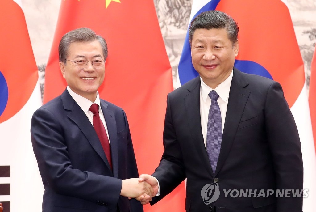 12月14日下午，在北京人民大会堂，韩国总统文在寅（左）和中国国家主席习近平握手合影。(韩联社)