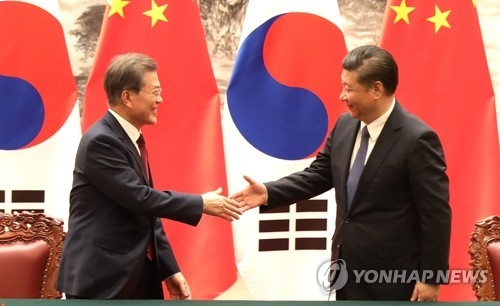12月14日下午，在北京人民大会堂，韩国总统文在寅（左）和中国国家主席习近平握手。(韩联社)