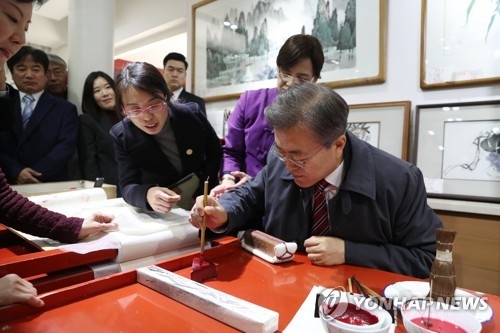 12月15日，在北京琉璃厂，文在寅体验绘制木板画。（韩联社）