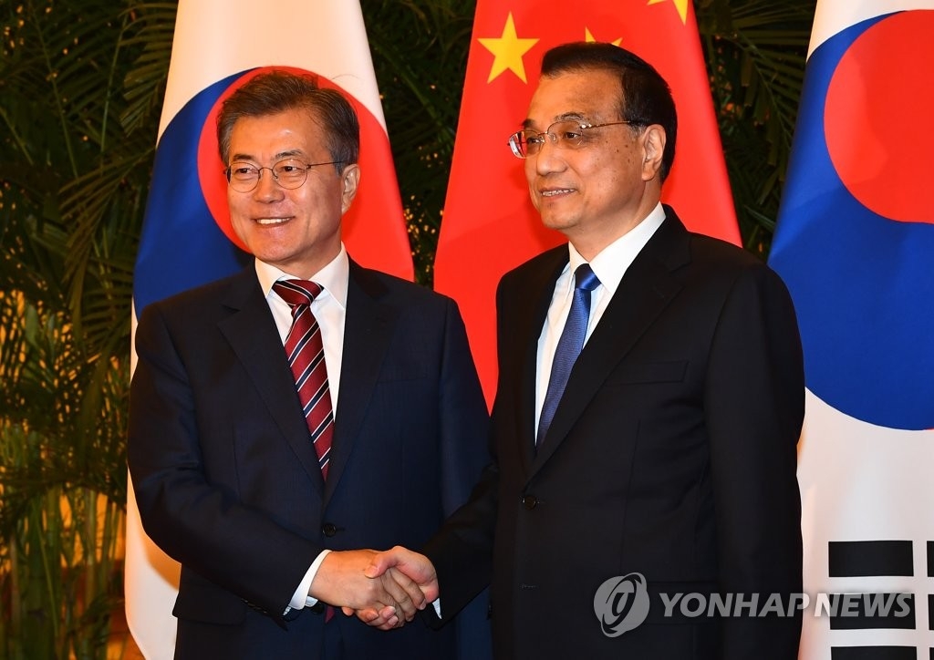 12月15日，在中国北京人民大会堂，韩国总统文在寅（左）会见中国国务院总理李克强，双方在会谈前亲切握手。 （韩联社）