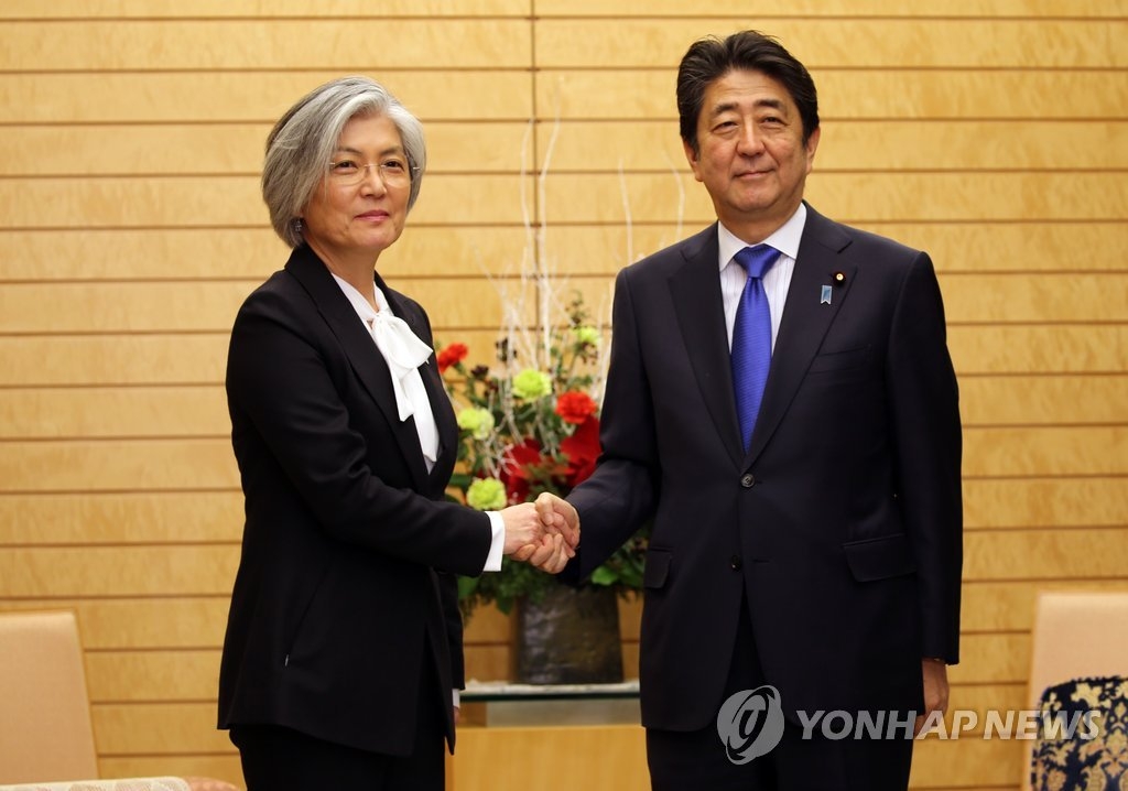 资料图片：12月19日下午，在东京，韩国外交部长官康京和（左）与日本首相安倍晋三握手合影。（韩联社）