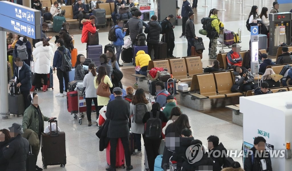 12月16日，在仁川机场，旅客排长队等候登机。（韩联社）