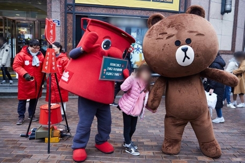 12月25日，人气歌手兼演员金在中（右）迎圣诞节在大邱参与韩国“慈善锅”活动，化身LINE Friends布朗熊在街头和捐款市民进行免费拥抱（Free hug）。（韩联社/经纪公司C-jeS娱乐提供）