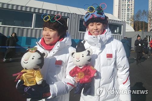 范可新（右）和周洋手持冬奥会吉祥物接受拍照。（韩联社）