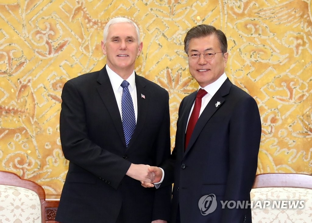 2月8日，在青瓦台，韩国总统文在寅（右）会见美国冬奥代表团团长、副总统迈克·彭斯，并握手合影。（韩联社）
