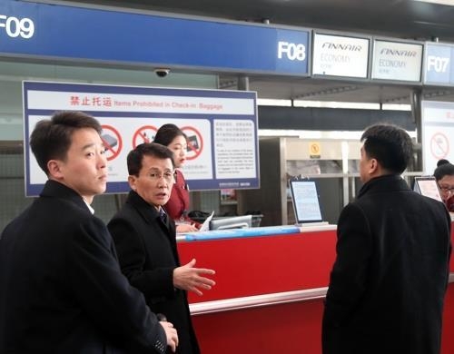 资料图片：崔强一（中间）一行正在办理登机手续。（韩联社）