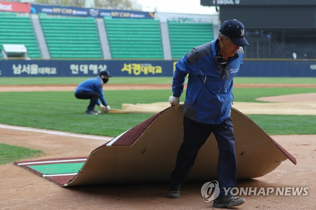 4月6日下午，在首尔蚕室棒球场，原定于下午6点30分举行的NC对抗斗山的2018韩国职业棒球联赛比赛因雾霾天被迫取消。图为体育场负责人在整理赛场。（韩联社）