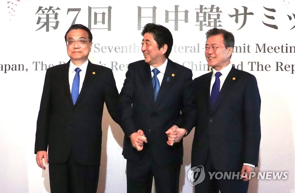 5月9日，韩中日领导人会议在东京举行，图为李克强（左起）、安倍晋三和文在寅牵手合影。（韩联社）