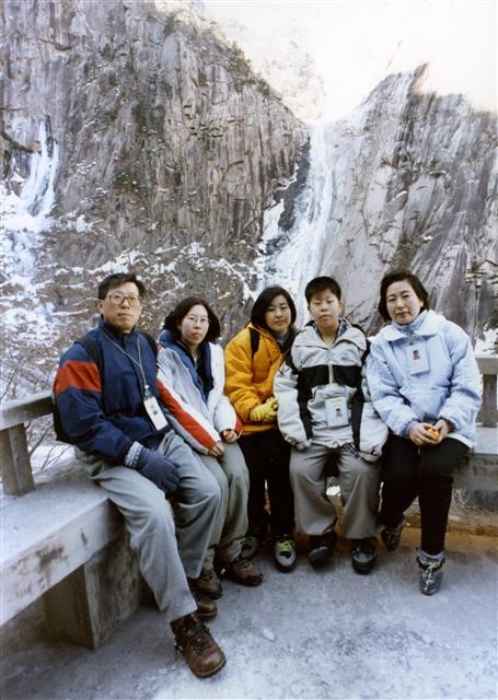 资料图片：1998年12月，在金刚山九龙瀑布前，郑梦宪（左一）、玄贞恩（右一）和三个子女合影留念。（韩联社）