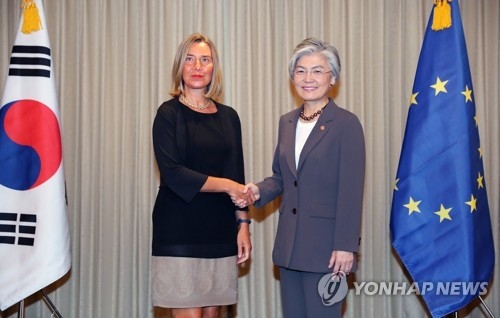 8月6日，在首尔，康京和（右）与莫盖里尼握手合影。（韩联社）