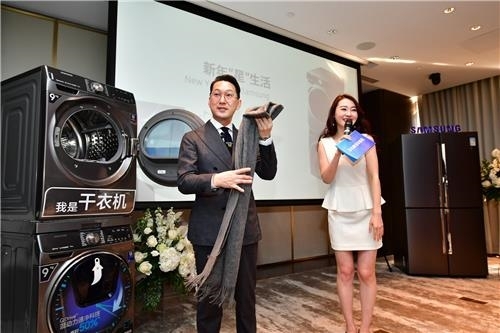 资料图片：1月24日，在北京举行的三星家电体验活动上，一位韩国知名时尚总监试用三星洗衣机和干衣机。（三星电子供图）