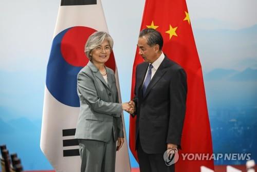 资料图片：8月20日，在北京，康京和（左）与王毅握手合影。 韩联社/外交部供图（图片严禁转载复制）