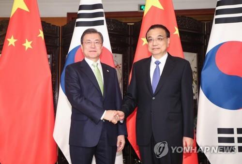 12月23日，在成都锦江宾馆，韩国总统文在寅（左）和中国国务院总理李克强在会谈开始前握手合影。 韩联社