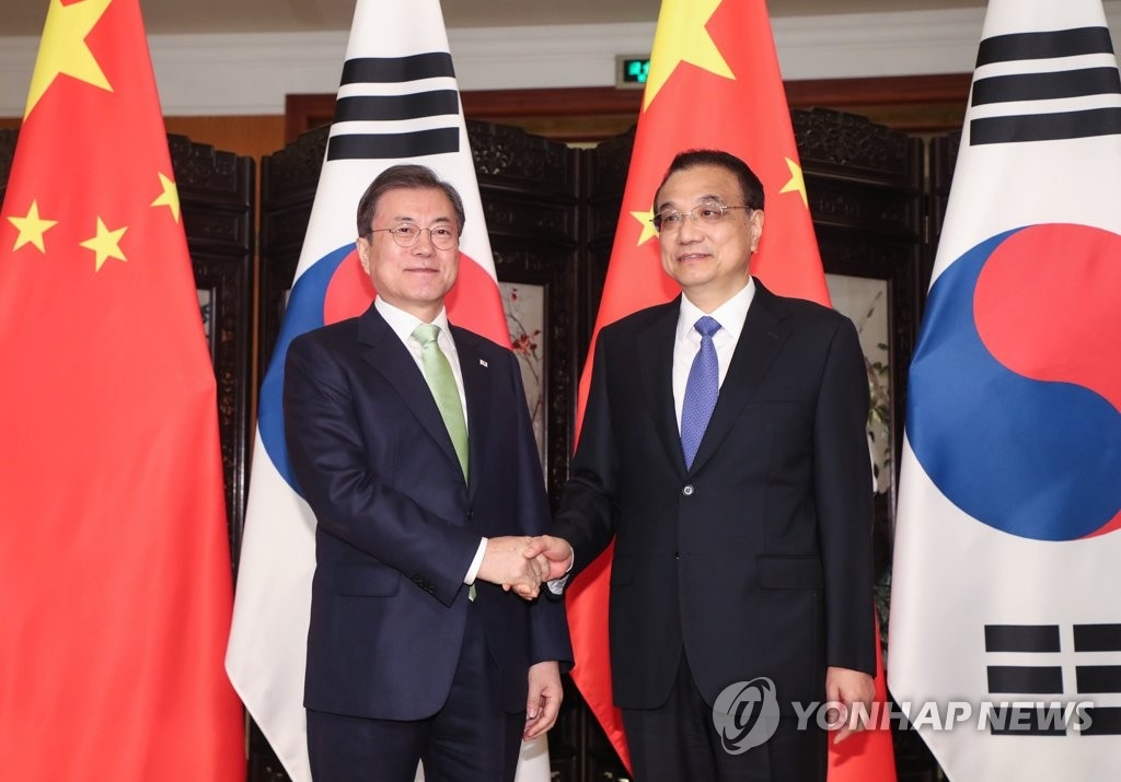 12月23日下午，在四川成都，韩国总统文在寅（左）和中国国务院总理李克强在会谈开始前握手合影。 韩联社