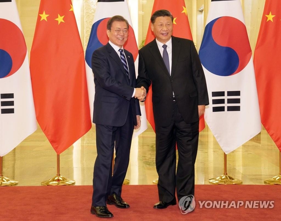 资料图片：12月23日，在北京，韩国总统文在寅（左）与中国国家主席习近平握手合影。 韩联社