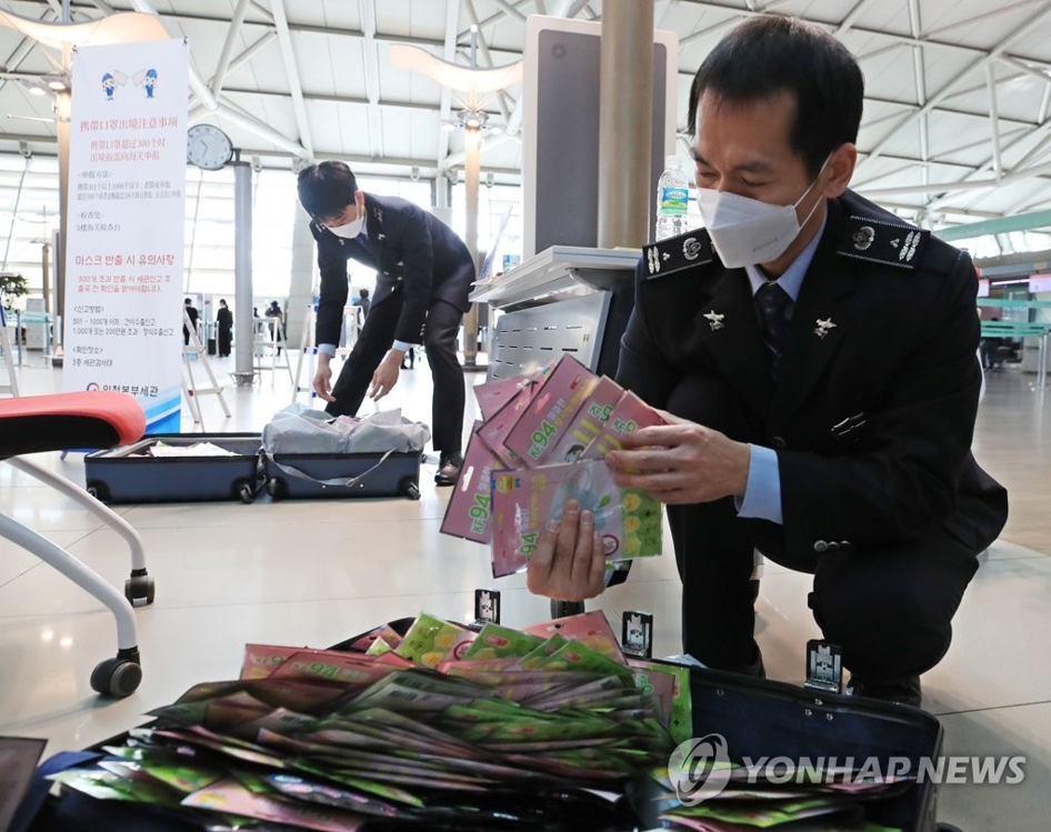 资料图片：2月6日，在仁川国际机场安检处，海关职员打开一游客行李箱，确认口罩数量。 韩联社