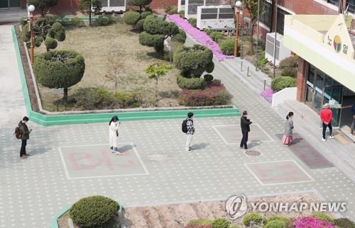 资料图片：4月15日，在首尔芦原区一投票站，选民们间隔一定距离排队等待投票。 韩联社