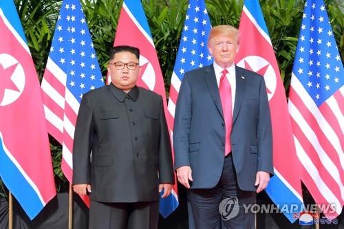 资料图片：2018年6月12日，在新加坡，朝鲜国务委员会委员长金正恩（左）和美国总统特朗普合影留念。 韩联社