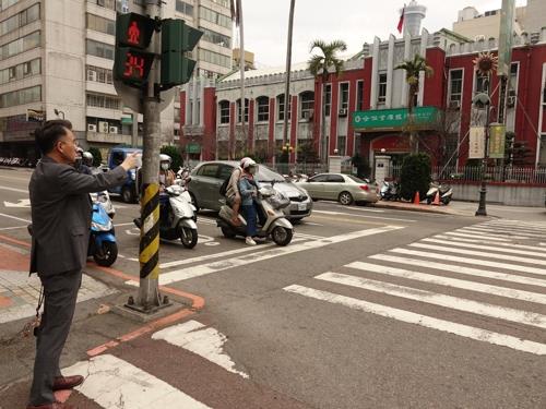 资料图片：2019年3月13日，金尚浩站在赵明河义举街头，手指赵明河义举前所在地。 金尚浩供图（图片严禁转载复制） 