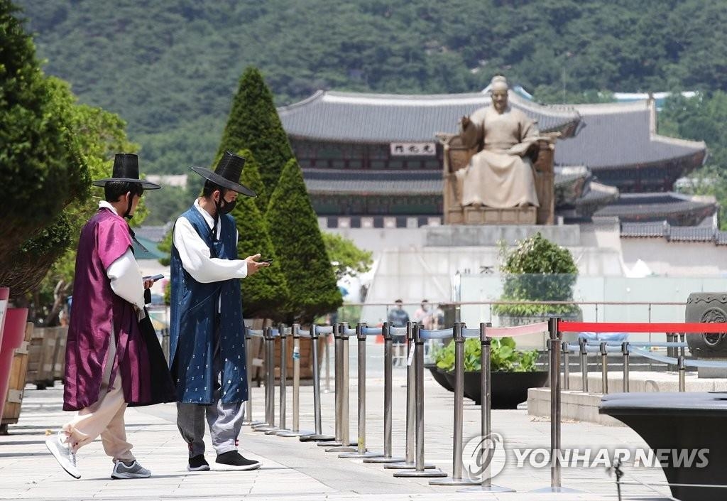 资料图片：6月14日，在首尔光化门广场，身穿韩国传统服饰——韩服的外国游客戴口罩出游。 韩联社