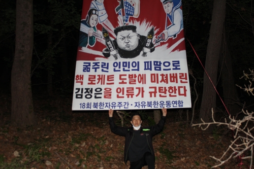 资料图片：韩国脱北者团体“自由北韩运动联合”代表朴相学高举反朝标语。 “自由北韩运动联合”供图（图片严禁转载复制）