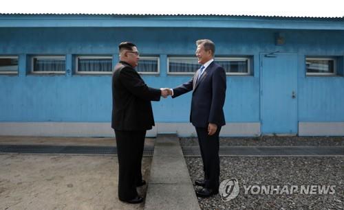 资料图片：2018年4月27日，在板门店，文在寅（右）与金正恩握手致意。 韩联社