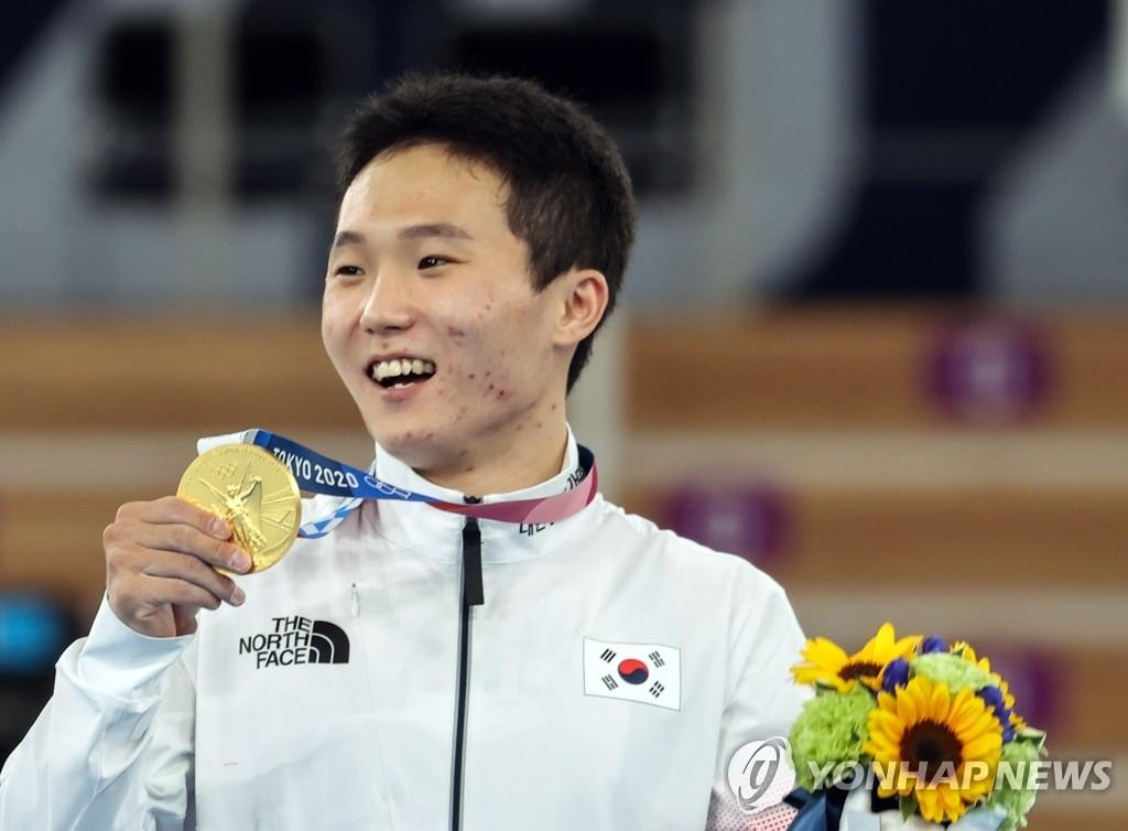 8月2日，在日本有明体操竞技场举行的东京奥运会男子跳马决赛中，韩国选手申在焕斩获金牌。图为申在焕在颁奖仪式上手持金牌庆祝夺金。 韩联社