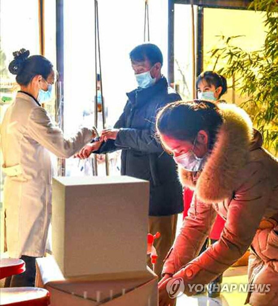 资料图片：据朝鲜劳动党机关报《劳动新闻》2020年12月4日报道，朝鲜近日防疫措施级别重新上调至最高级别“超特级”，每日对室内空间多次进行消毒，并限制各地区人员流动。图为平壤建具技术交流社对进出人员进行测温。 韩联社/《劳动新闻》官网截图（图片仅限韩国国内使用，严禁转载复制）