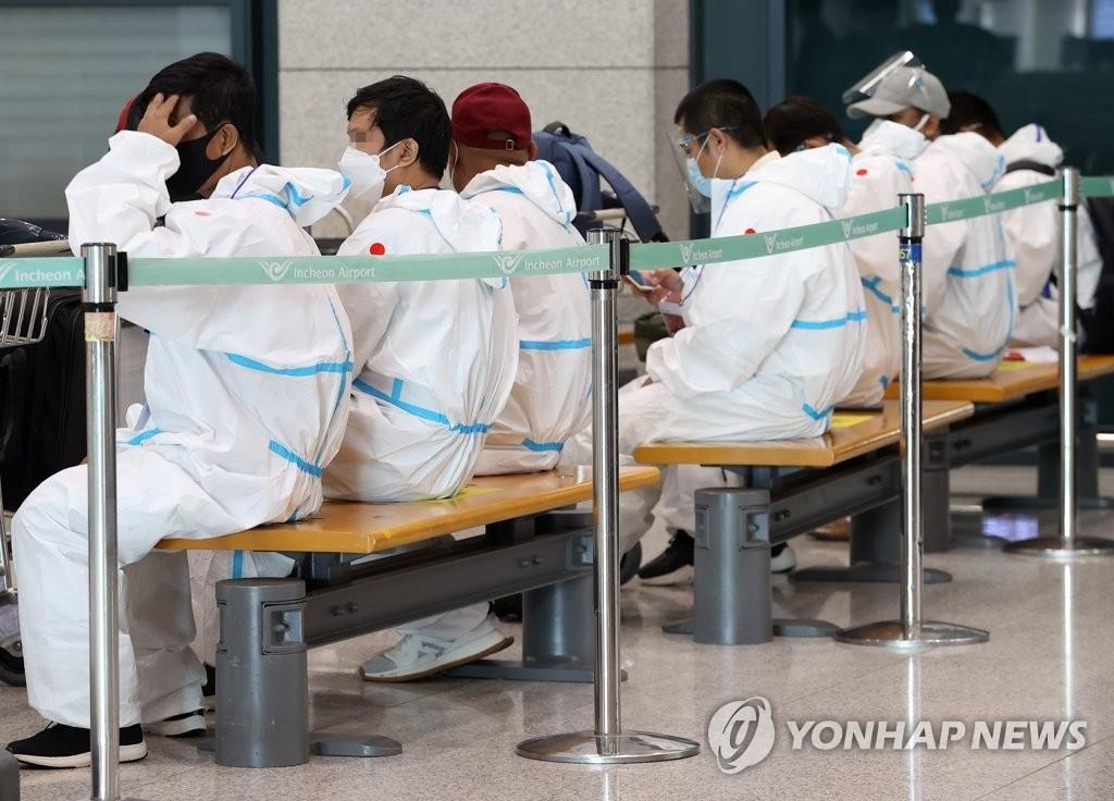 资料图片：外籍旅客身穿防护服等候边检。 韩联社