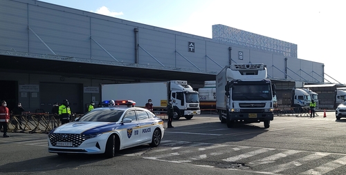 1月13日，在仁川国际机场货运站，装载新冠口服药的两辆卡车在警车的护送下驶离。 韩联社