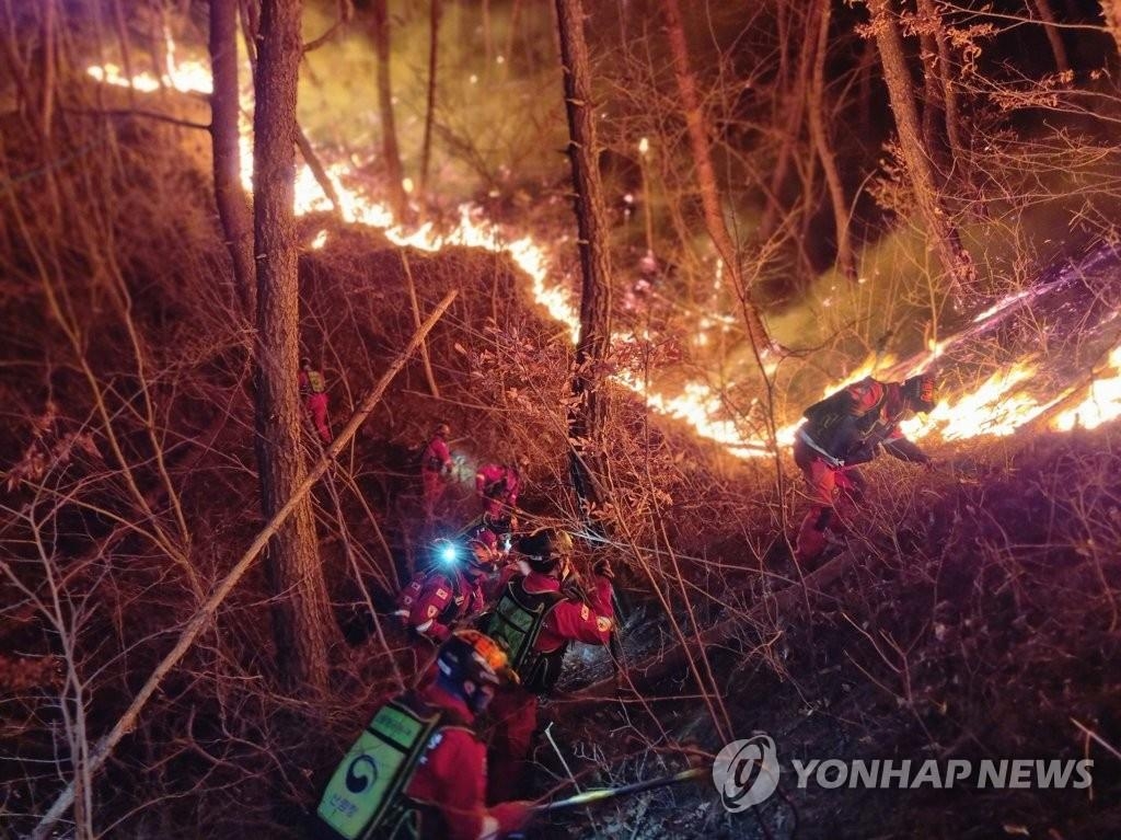 资料图片：2月28日，在庆尚南道陕川郡栗谷面，山林厅山林航空本部所属空中救火队员们开展灭火工作。当地一座山当天发生火灾，过火面积达到600公顷。 韩联社