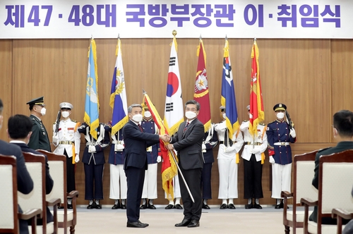 5月11日，在防长离任荣退暨新任就职仪式上，李钟燮从徐旭手中接过国防部旗帜。 韩联社/《国防日报》供图（图片严禁转载复制）