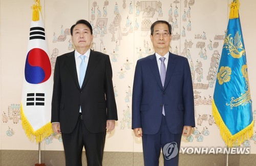 5月21日，在首尔龙山总统办公室大楼，韩国总统尹锡悦（左）向新任国务总理韩悳洙颁发任命书后合影留念。 韩联社