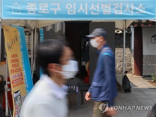 资料图片：5月23日，在首尔钟路区，人们走过一处新冠筛查诊所。 韩联社