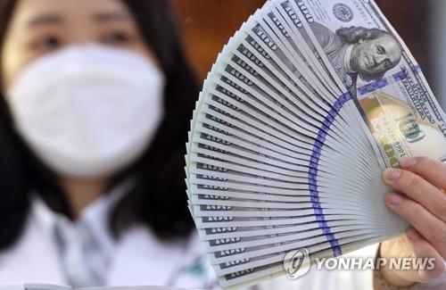 6月23日，在首尔市的韩亚银行总行，工作人员展示美元钞票供媒体拍照。 韩联社