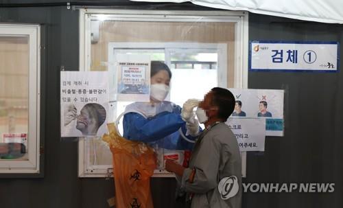 资料图片：6月29日，在设于首尔站广场的新冠临时筛查诊所，一位市民正在接受检测。 韩联社