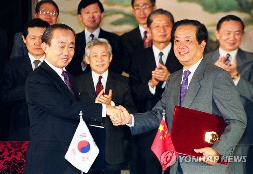 资料图片：1992年8月24日，在北京钓鱼台国宾馆，李相玉（左）和钱其琛签署建交联合公报后握手言欢。 韩联社